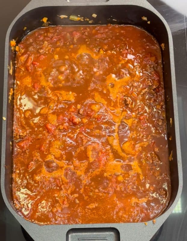 Tomatenstücke und Rinderfond zum Hackfleisch geben