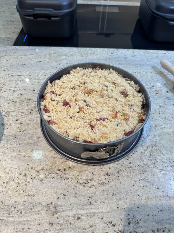 Streusel über den Pflaumen verteilen