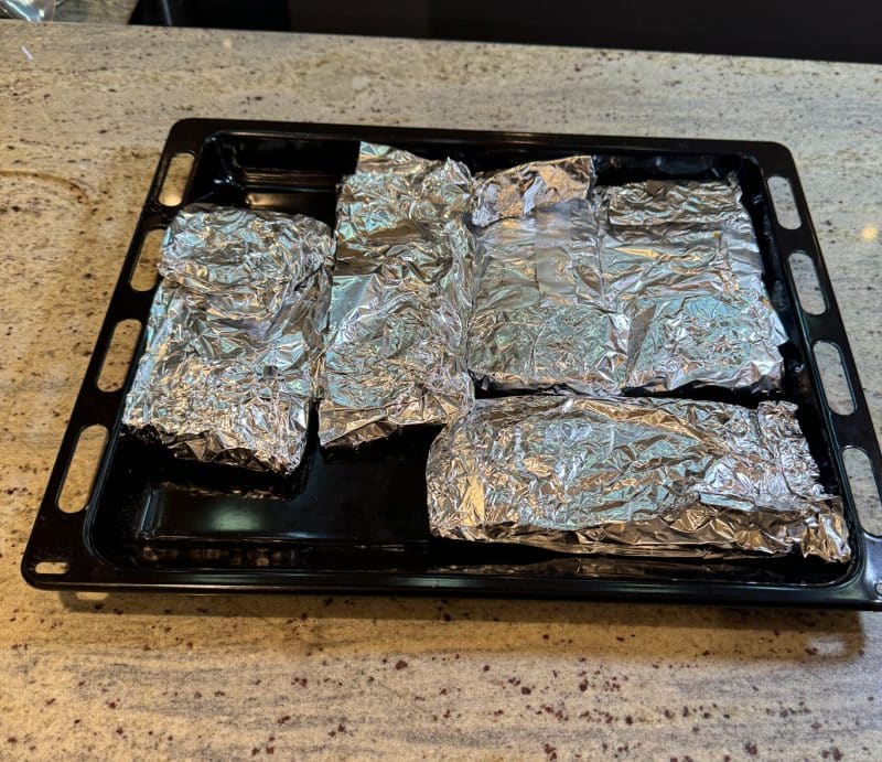 Die Spareribs mit der Knochenseite nach unten auf ein Backblech legen und für ca. 3 Stunden im Ofen garen (je nach Dicke der Rippchen kann die Zeit variieren).
