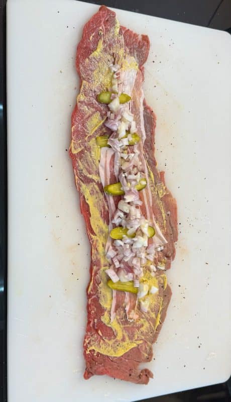 Auf jede Roulade lege ich 1-1 ½ Scheiben Speck, längs geschnittene Gewürzgurken und fein gewürfelte Schalotten.