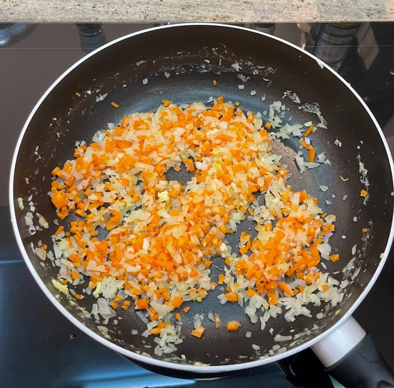 o Erhitze in derselben Pfanne etwas Pflanzenöl. Gib die gehackten Zwiebeln hinzu und brate sie 2-3 Minuten, bis sie weich werden. Füge die Karotten und den gehackten Knoblauch hinzu und brate weitere 2-3 Minuten, bis die Karotten weich, aber noch bissfest sind.