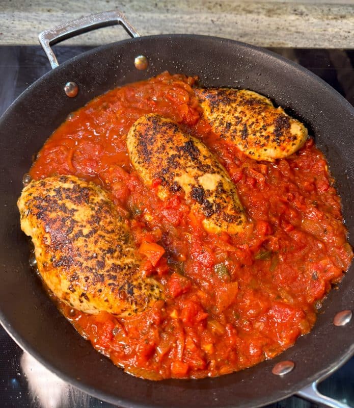 Hähnchenbrustfilets in Pfanne, umgeben von selbstgemachter Tomatensauce