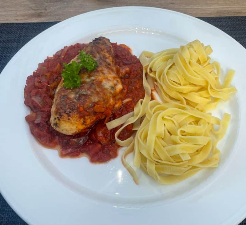 Hähnchenbrustfilet mit Tomatensauce und Käse, serviert mit Nudeln