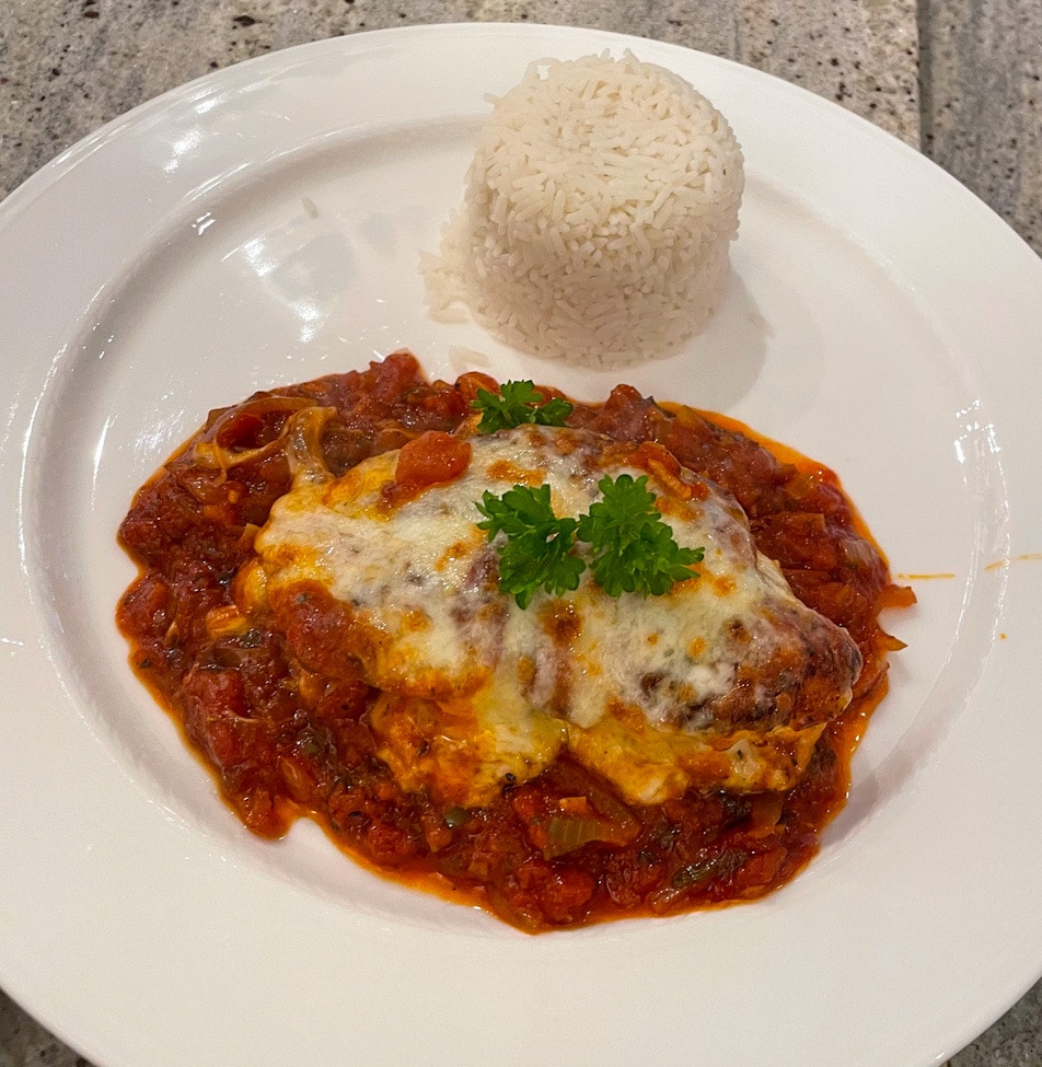 Hähnchenbrustfilet mit Tomatensauce und geschmolzenem Käse, serviert mit Reis