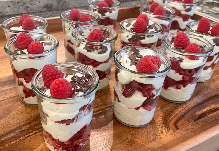 Dessert wird mit frischen Himbeeren und Zartbitterschokoladenraspeln garniert