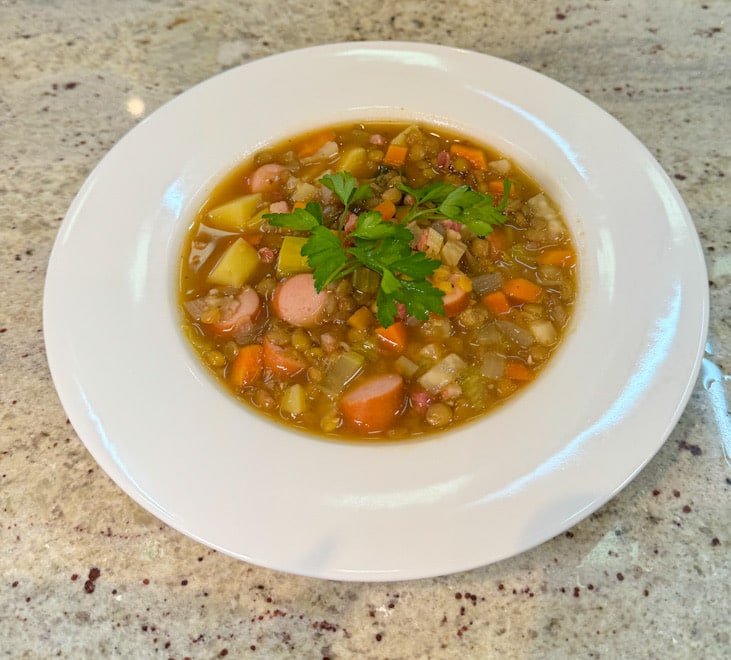 eller mit klassischer Linsensuppe, serviert mit Würstchen und frischer Petersilie