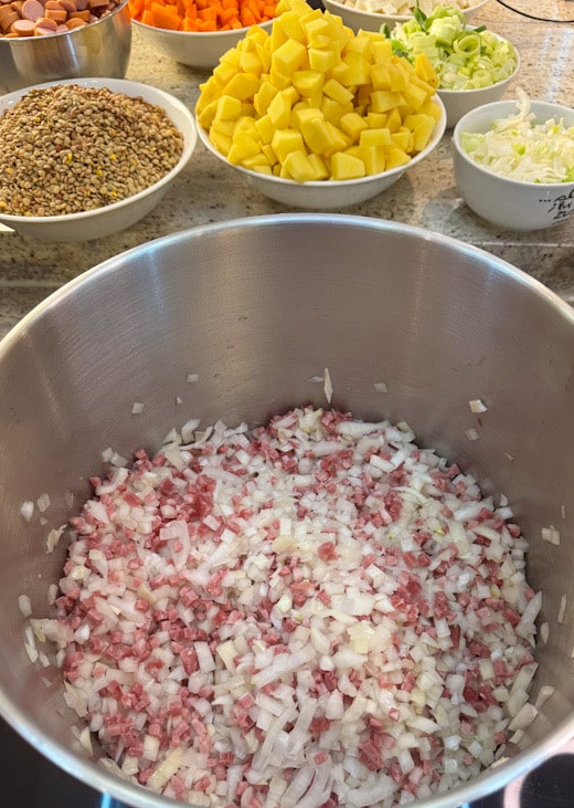 Speck und Zwiebeln in einem Topf anbraten – erster Schritt für die Linsensuppe