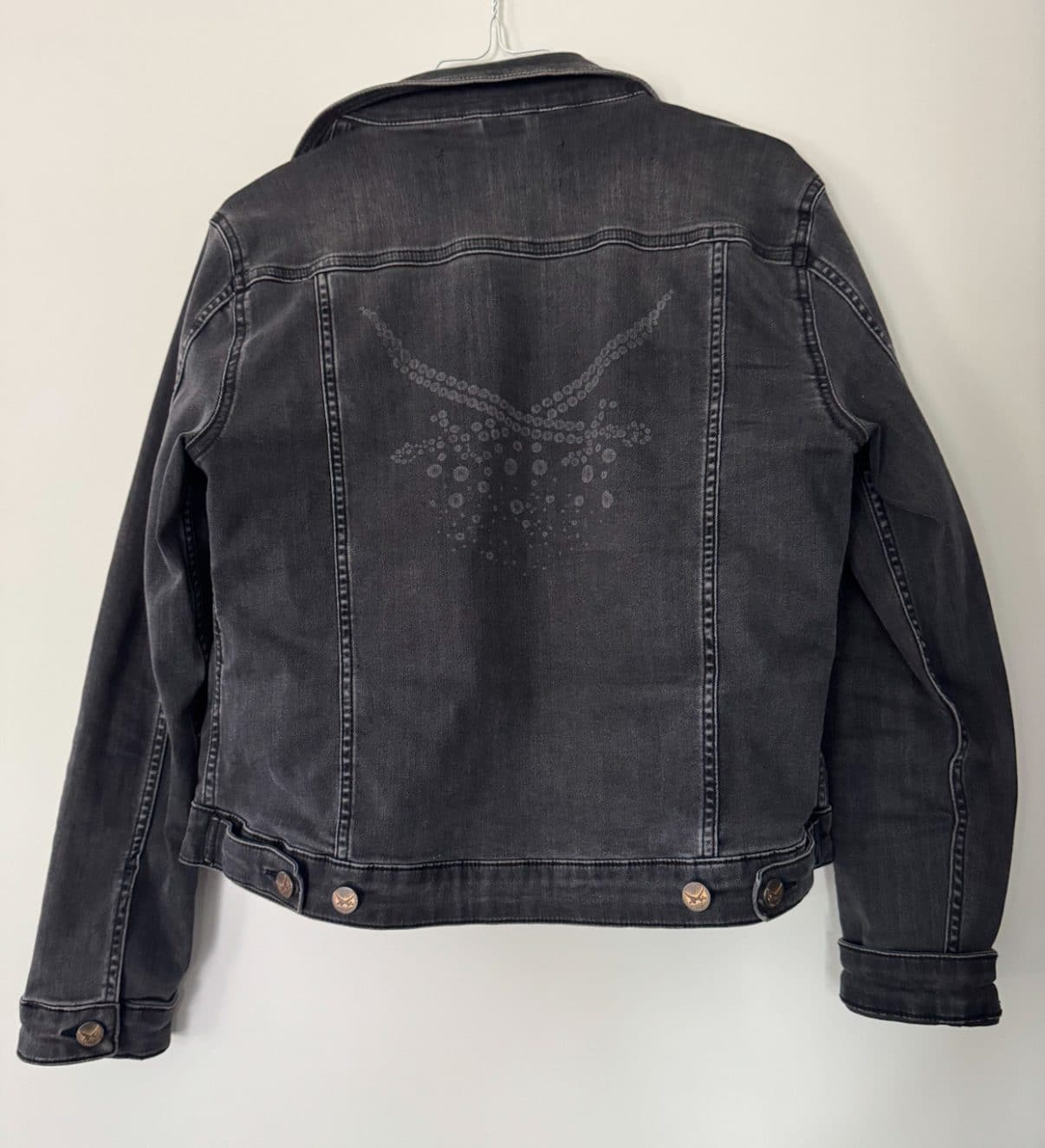 Rückansicht einer schwarzen Jeansjacke mit aufgedrucktem Sansibar-Logo im dezenten Used-Look