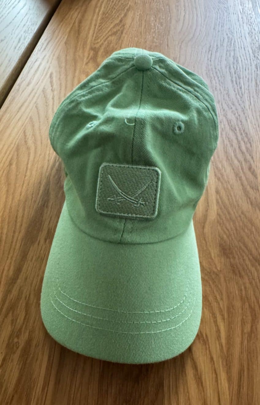 Grüne Cap mit Sansibar-Logo, ausgestellt auf einem Holztisch