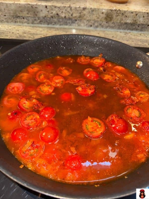 Sauce mit halbierten Tomaten nach dem Ablöschen mit Weißwein und Aufgießen mit Fond