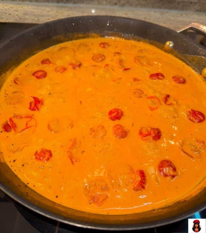 Cremige Sauce mit Tomaten, Frischkäse und Parmesan in der Pfanne nach dem Aufkochen