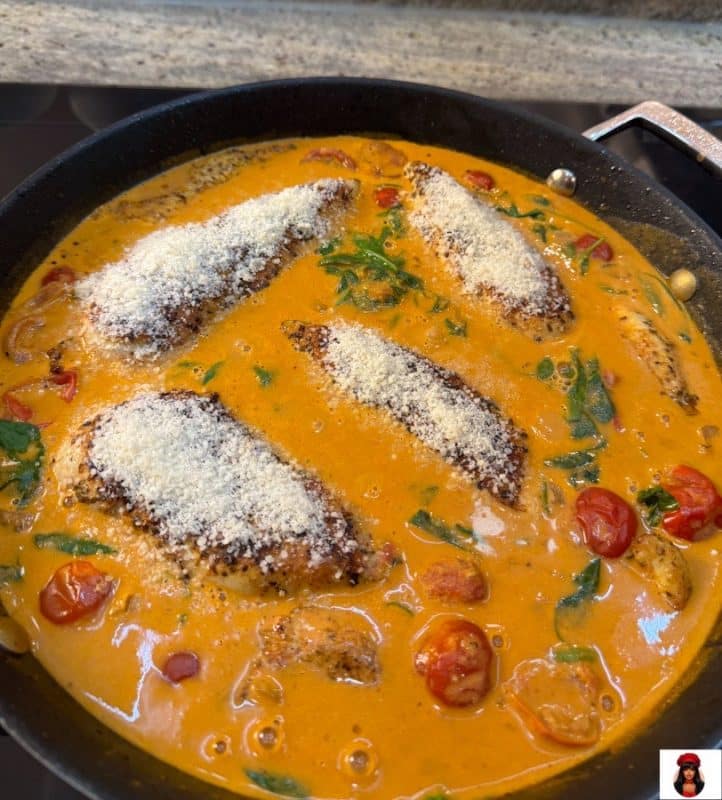 Hähnchenbrustfilets in cremiger Sauce in der Pfanne, mit Parmesan bestreut, bereit für den Ofen