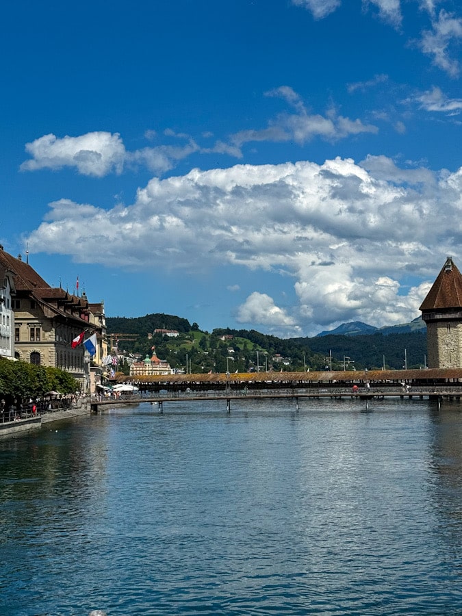 Blick auf die Kapellbrücke und den Wasserturm in Luzern mit Stadtpanorama und Bergen