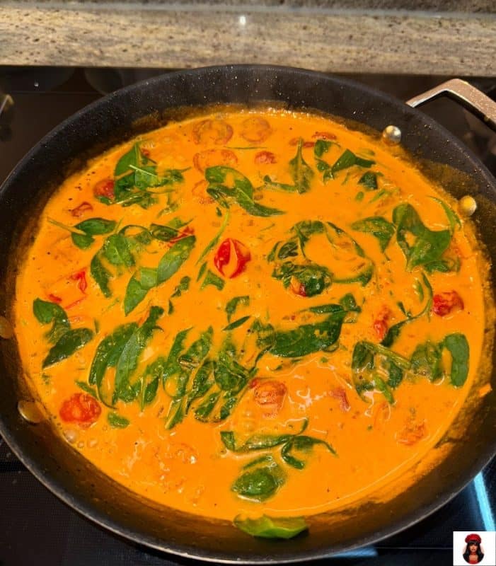 Frischer Spinat in cremiger Parmesan-Tomatensauce untergehoben in der Pfanne