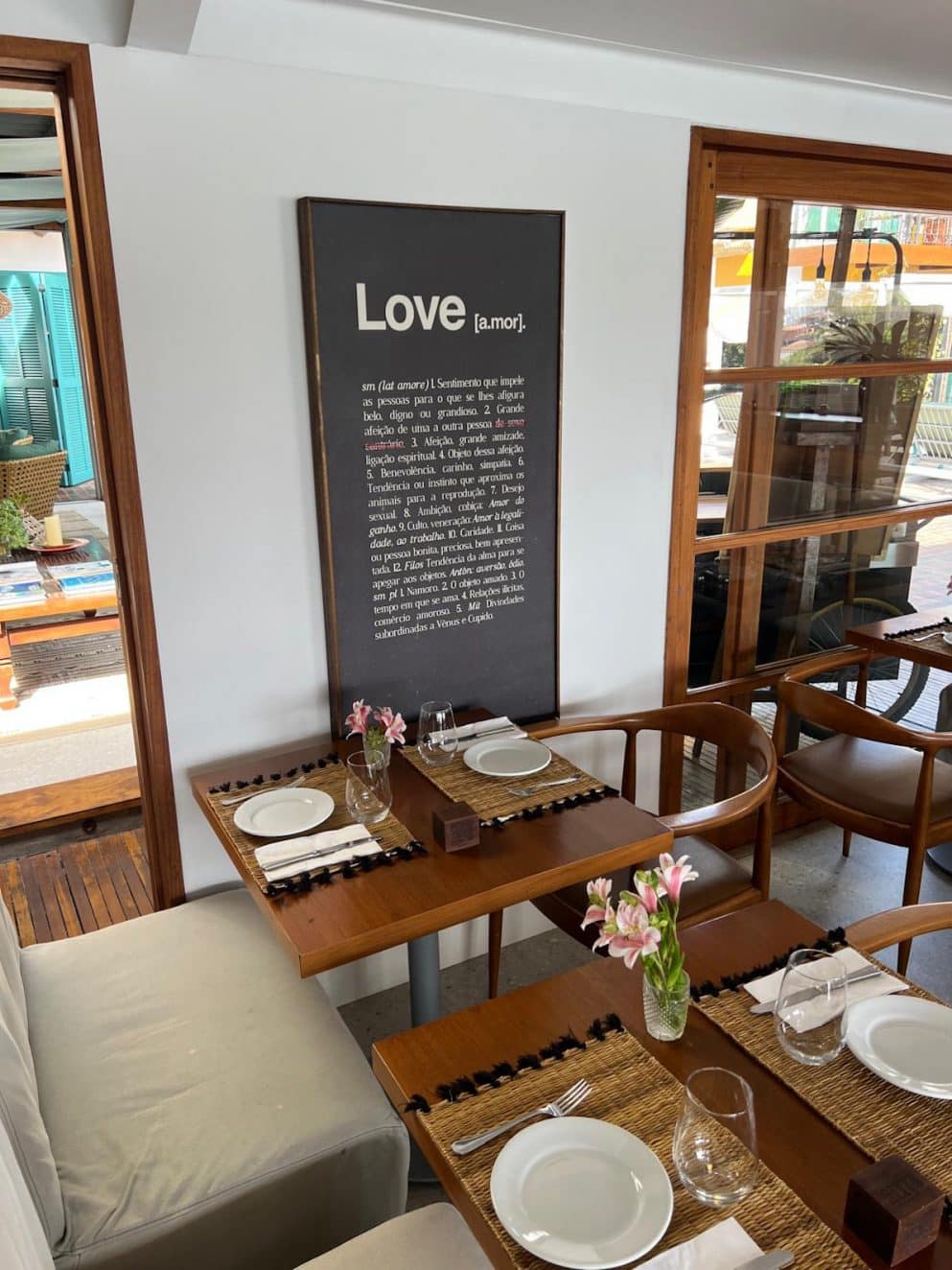 Innenbereich des Altto Ristorante & Lounge im Vila d’Este Hotel in Búzios, Brasilien – Wandbild „Love [a.mor]“ und liebevoll gedeckter Tisch.

Interior of Altto Ristorante & Lounge at Vila d’Este Hotel in Búzios, Brazil – wall art “Love [a.mor]” and beautifully set table.
