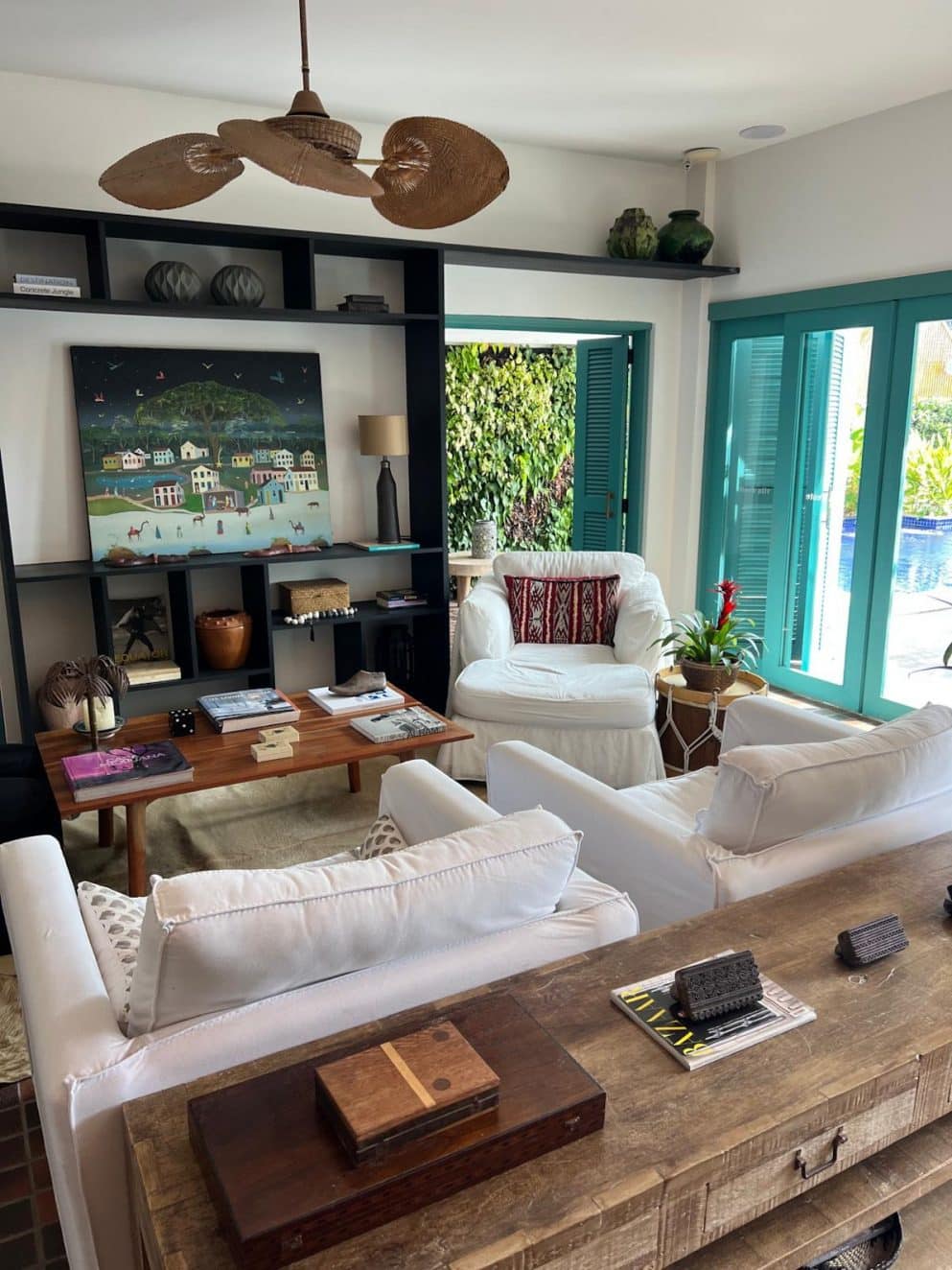 Lounge im Vila d’Este Hotel in Búzios, Brasilien – gemütlicher Sitzbereich mit weißen Sesseln, Kunst und Blick in den Garten Lounge area at Vila d’Este Hotel in Búzios, Brazil – cozy seating space with white armchairs, artwork, and garden view