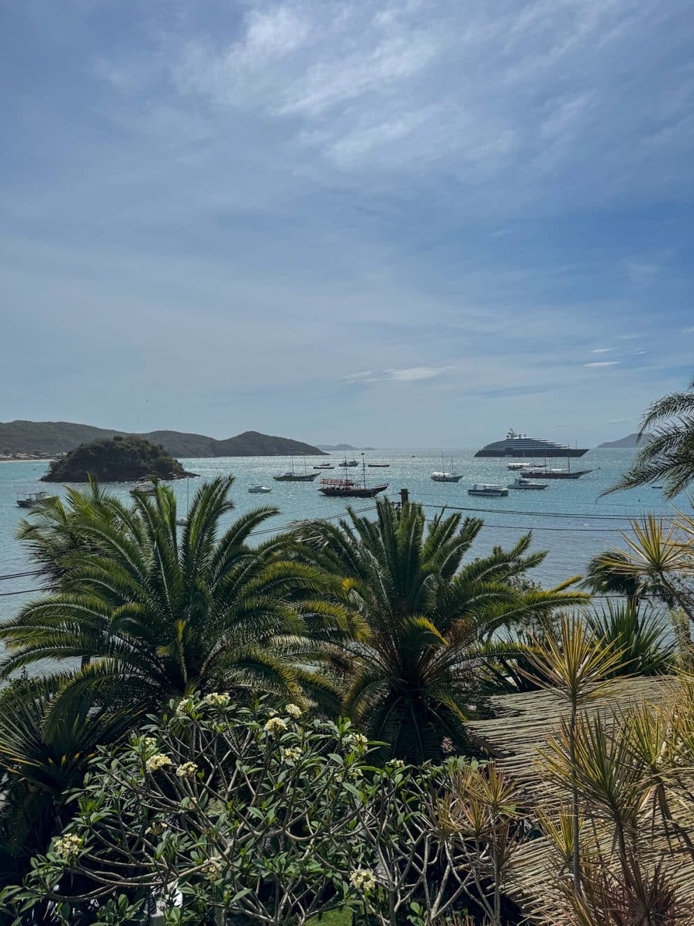 Blick über Palmen auf die ruhige Bucht von Búzios im Vila d’Este Hotel, Brasilien