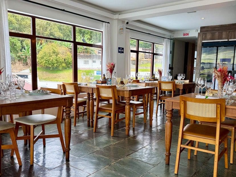 Heller Gastraum im ersten Stock des Convés Restaurants in São Francisco do Sul, Brasilien, mit gedeckten Tischen und großen Fenstern.