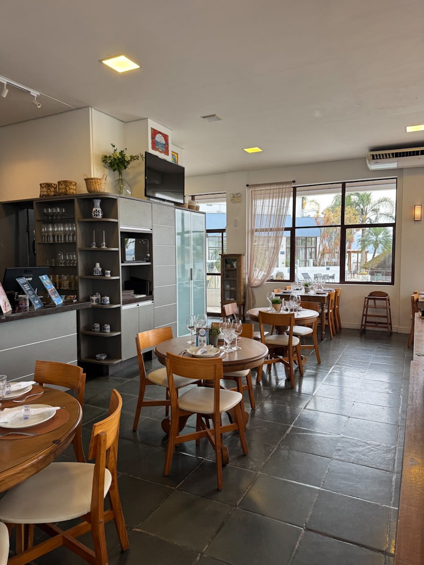 Lichtdurchfluteter Gastraum im Convés Restaurant mit runden Holztischen und großen Fenstern