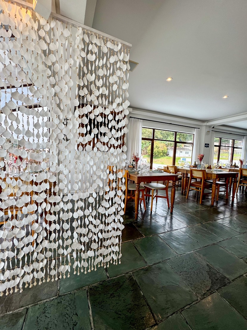 Detailansicht im ersten Stock des Convés Restaurants in São Francisco do Sul, Brasilien, mit strukturierter Wand und Blick in den hellen Gastraum.